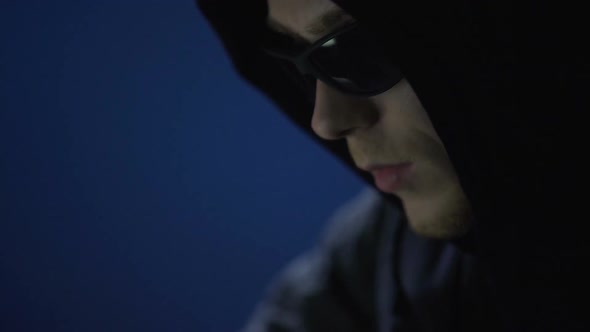 Closeup of Man in Sunglasses Committing Crime, Illegally Using Company Computer