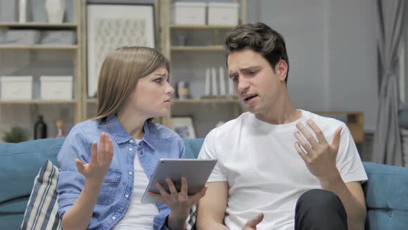 Upset Young Couple Reacting To Financial Loss While Using Tablet