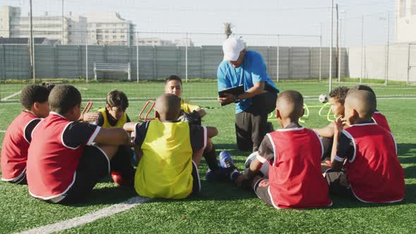 Soccer kids in cercle and listening to the coach in a sunny day