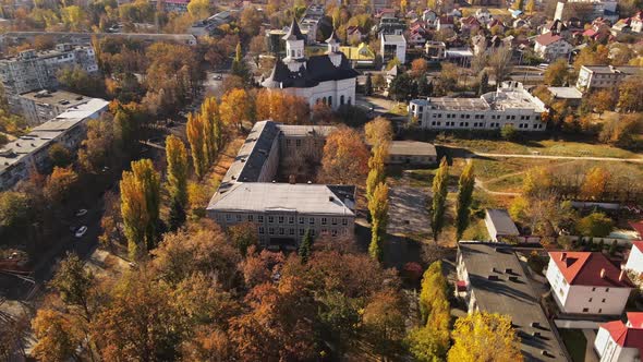 Aerial drone view of Chisinau in autumn, Moldova. Yellowed vegetation, multiple buildings, church, r