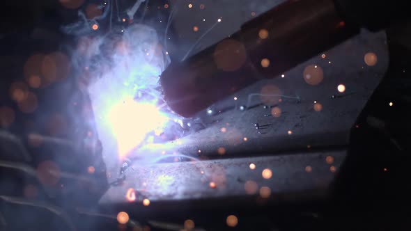 Slow motion of arc welder shooting hot sparks.