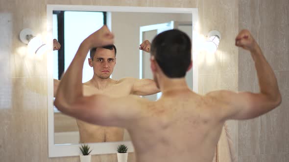 Man Looks at the Muscles on a Mirror