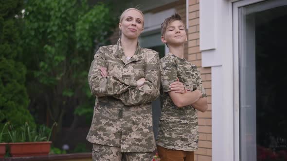 Portrait of Brave Confident Military Mother and Teenage Son in Khaki Camouflage Crossing Hands