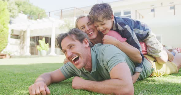 Portrait of happy caucasian couple with son lying in garden