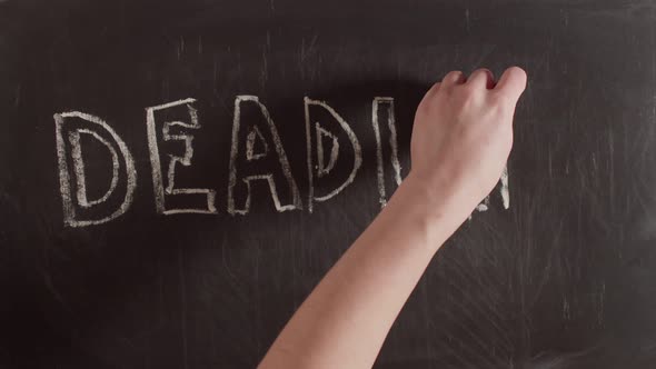 Word deadline is written with a hand on a chalkboard. On blackboard is written word deadline