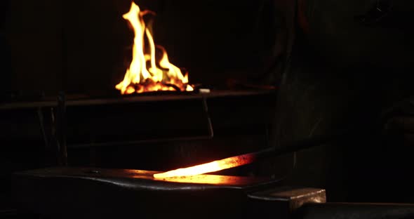 Mid-section of blacksmith working on a iron rod