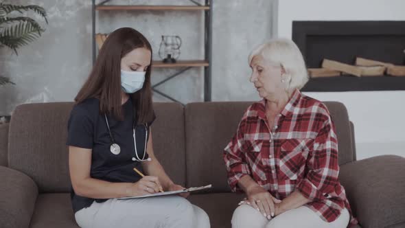 Young Doctor Examining Elderly Lady Complains of Back Pain, Writing Diagnosis