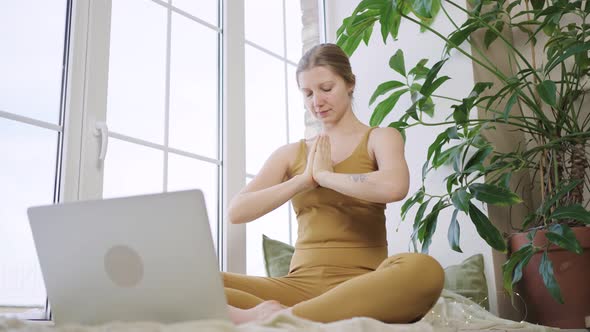 Blonde Woman in Sport Outfit Meditates Watching Tutorial