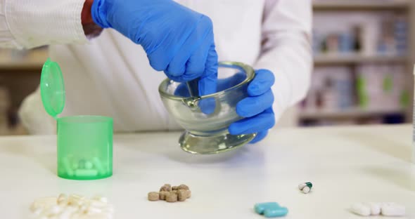 Pharmacist grinding medicine in mortar and pestle