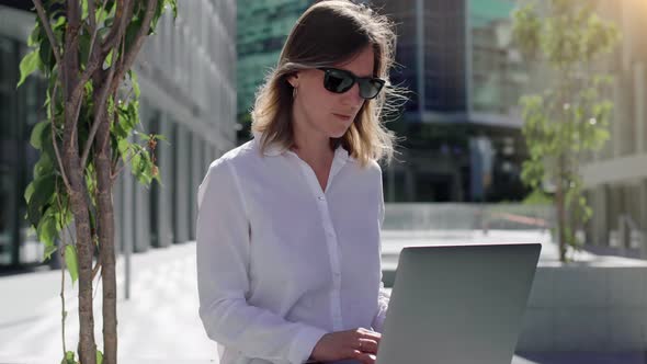 Focused businesswoman working on laptop computer in business district. 