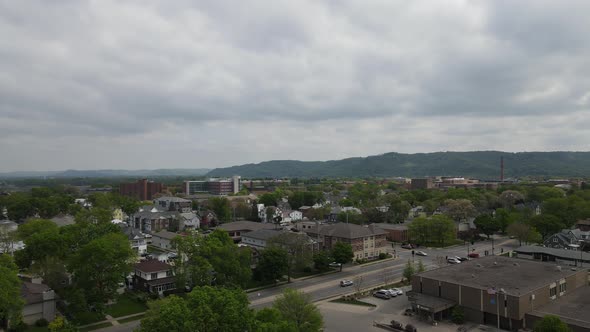 Aerial view of small midwest city on a cloudy day in summer. Mountains and forest in background.