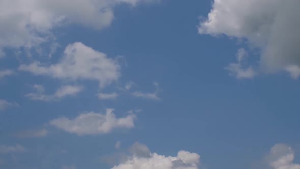 A timelapse of clouds in a blue sky. One cloud is gray in color, it usually rains from such clouds
