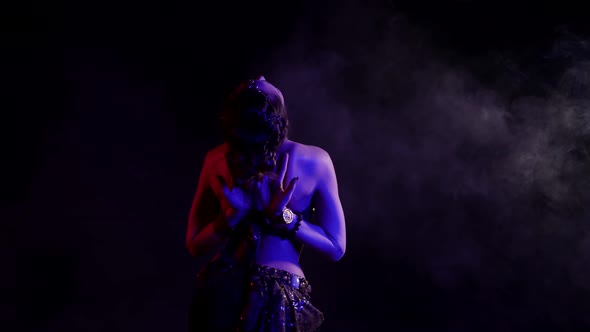 A Woman Seen From the Back Dancing an Oriental Dance in a Smoky Studio on a Black Background Makes