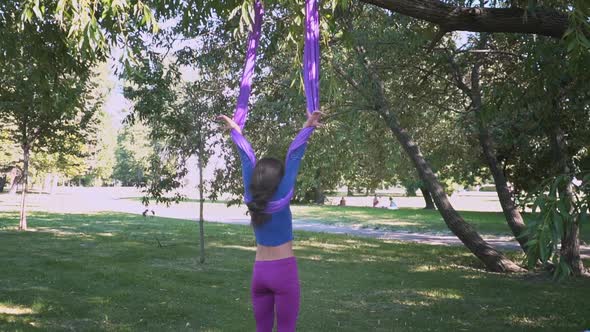 Young Beautiful Sportswear Woman Training Aero Stretch Swing Sunny City Park Hanging Upside Down