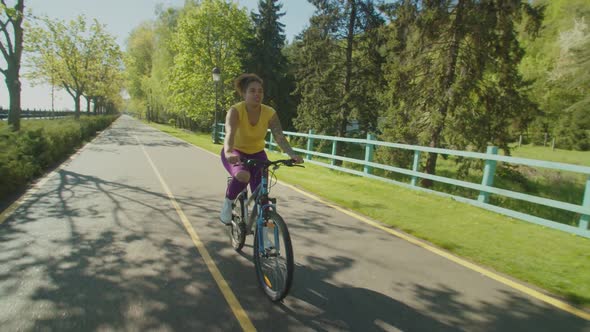 Relaxed Hipster Black Woman Cycling Through Summer Park