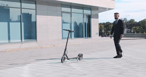 Businessman in Suit Coming To Electric Scooter and Riding Away