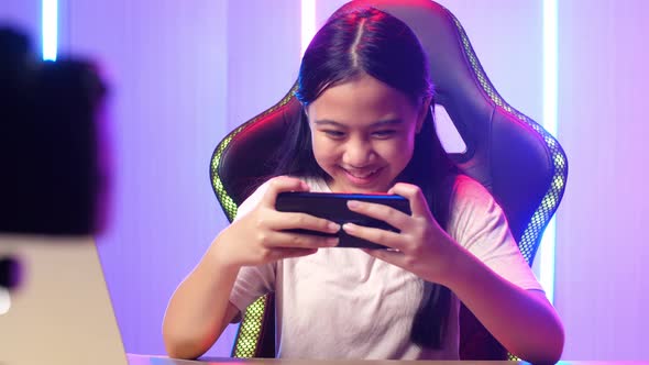 Excited Asian Kid Girl Playing Video Game With Mobile Phone While Live Stream