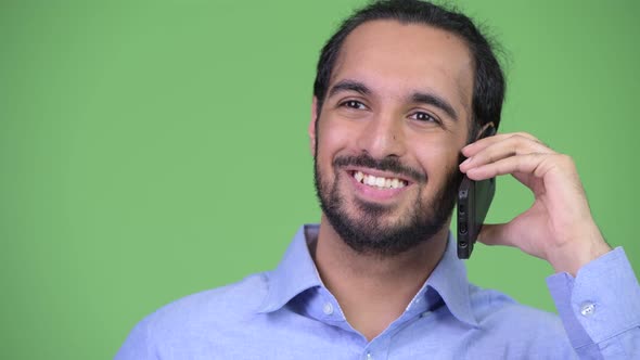 Young Happy Bearded Indian Businessman Thinking While Talking on the Phone