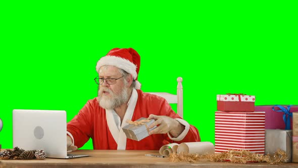 Santa claus using laptop while checking gift box