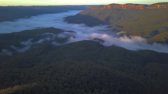 The Three Sisters rocks formation at Blue Mountains with view of clouds covering the rainforest tree