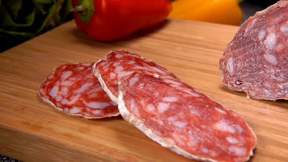 Close-up Panorama of a Knife Cut a Delicious Dry Sausage Into Slices on a Board