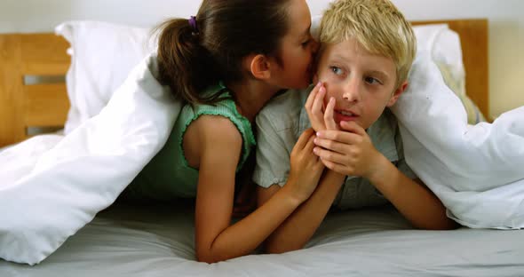 Siblings interacting with each other on bed in bedroom