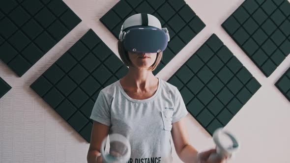 Young Woman in a VR Helmet Plays a Game at Home