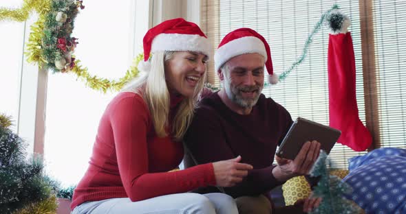 Happy caucasian mature couple making video call in room full of christmas decorations