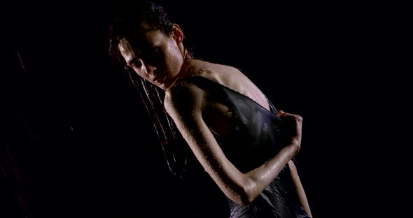 Anorexic Woman Is Posing in Darkness Under Water Stream, Wriggling Her Body, Looking at Camera