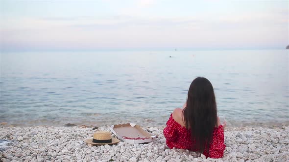 Woman Having a Picnic with Pizza on the Beach