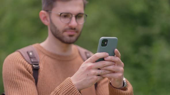 A Man Walks in the Woods and Writes a Message on His Mobile Phone