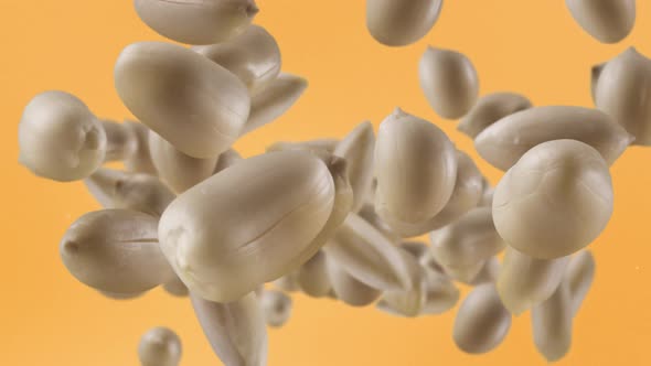 Flying of Roasted Peanuts in Pale Orange Background