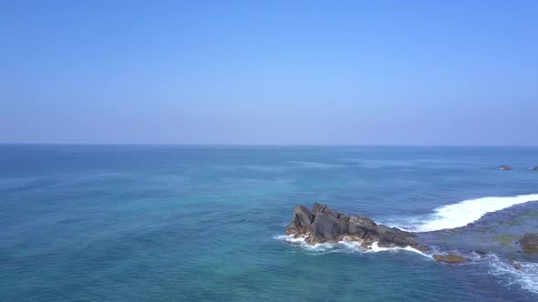 Lady Meditates on Large Rocky Cliff at Endless Blue Ocean