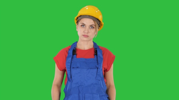 Young construction woman in hardhat walking on a Green