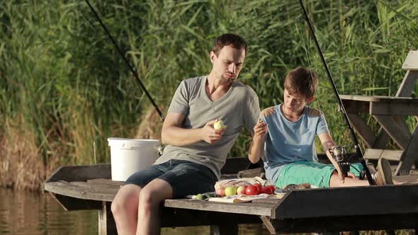 Hipster Father and Son Enjoying Picnic By the Pond