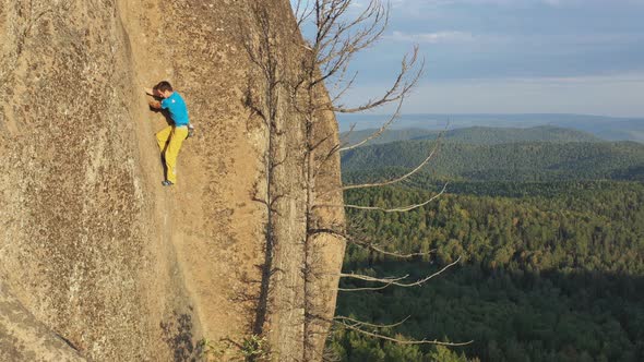 Aerial Shot of a Young Man Climbing a Rock Crack To the Top of a Mountain Without Insurance