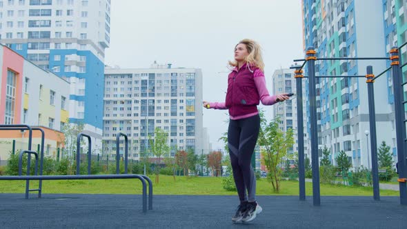 Blonde Girl in Sportswear Jumping Rope Outside