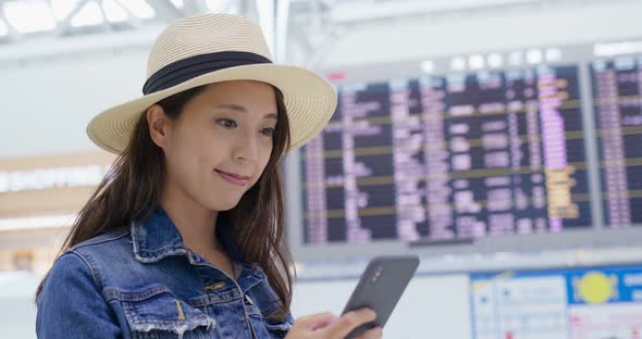 Woman check the flight schedule on cellphone in the airport