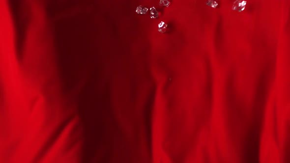 Acrylic cubes rolling down on red fabric, Slow Motion