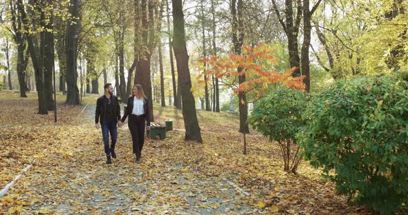 Couple Walking in Autumn Park, Rejoicing While Embracing and Kissing Each Other