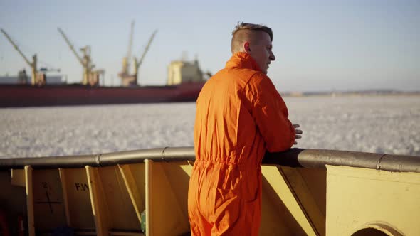 Young Man in Orange Uniform Traveling on Board of the Ship in Winter