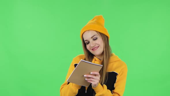 Portrait of Modern Girl in Yellow Hat Is Standing and Thinking, Then Happy Writing with Pencil in