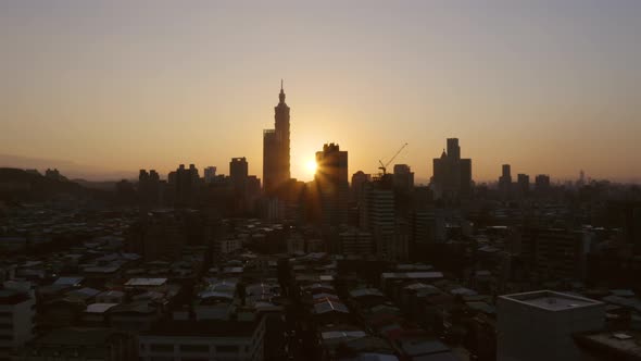 Drone shot of Taipei by sunset on a clear evening with Taipei 101 in the middle. The sun is really l