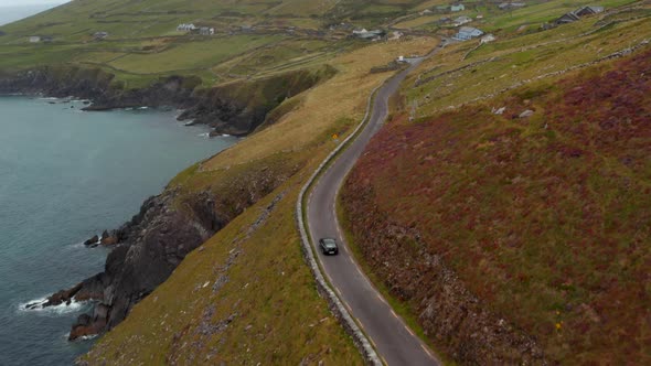 High Angle View of Single Car Driving on Narrow Country Road Along Sea Coast