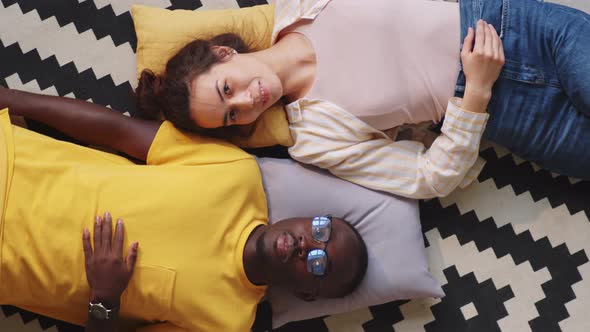 Multiethnic Couple Lying on Floor at Home and Posing for Camera