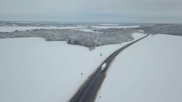 Drone. Coniferous forest, road and village. Asphalt. Winter landscape.