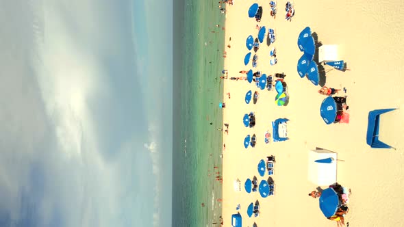 Vertical Aerial Video Mini Drone Flying Over People On The Beach To Ocean