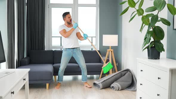 Man Cleaning the House and Having Fun Dancing with a Broom