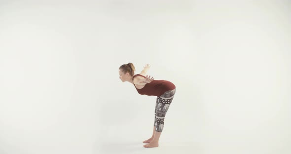 Young attractive woman performing Yoga routine on a white studio background