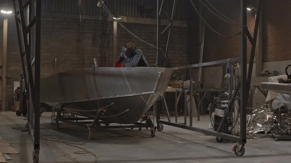 Worker Welding Boat in Garage